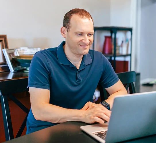 A person sitting at a table using a laptop.
