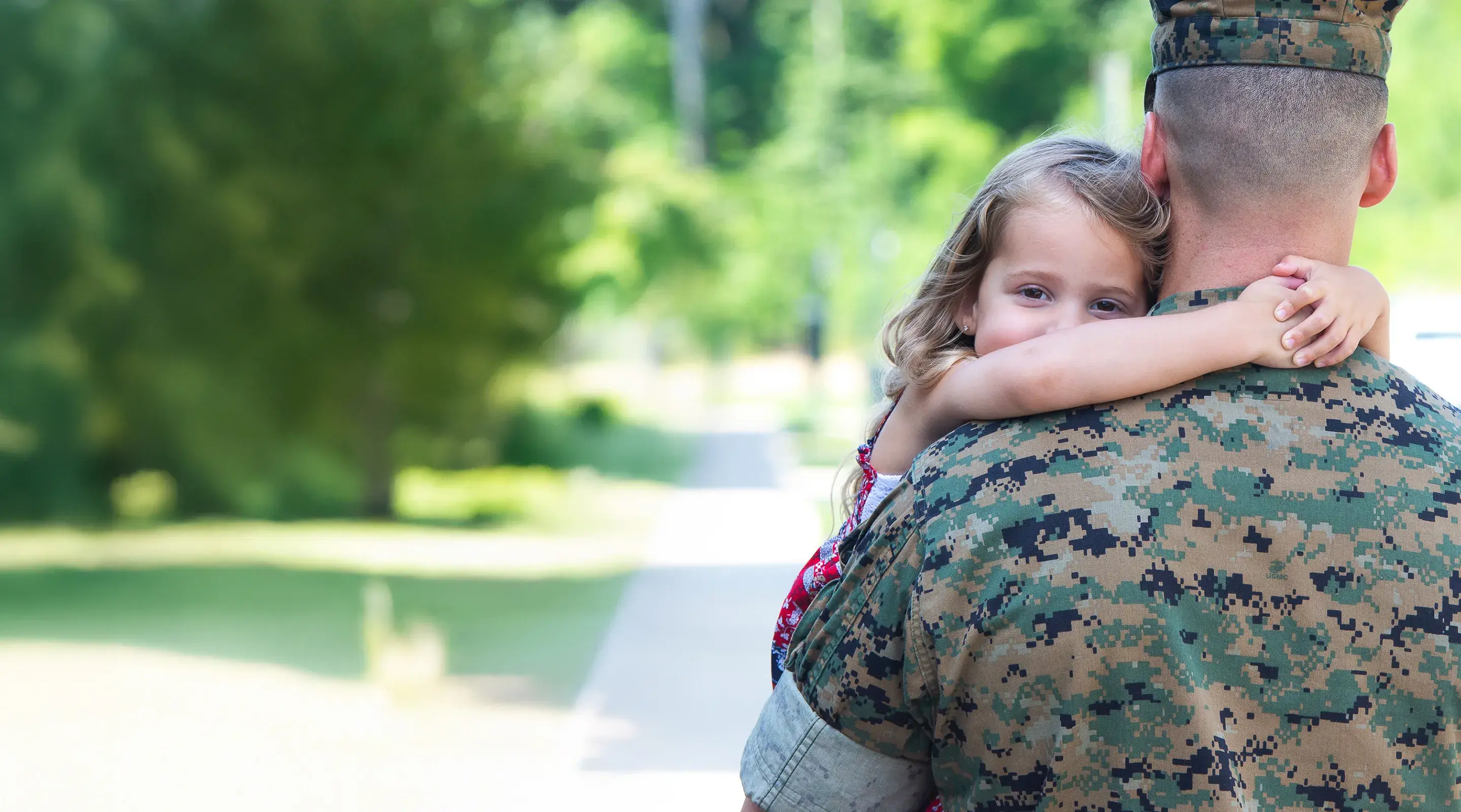 Image of a military personnel hugging a young child