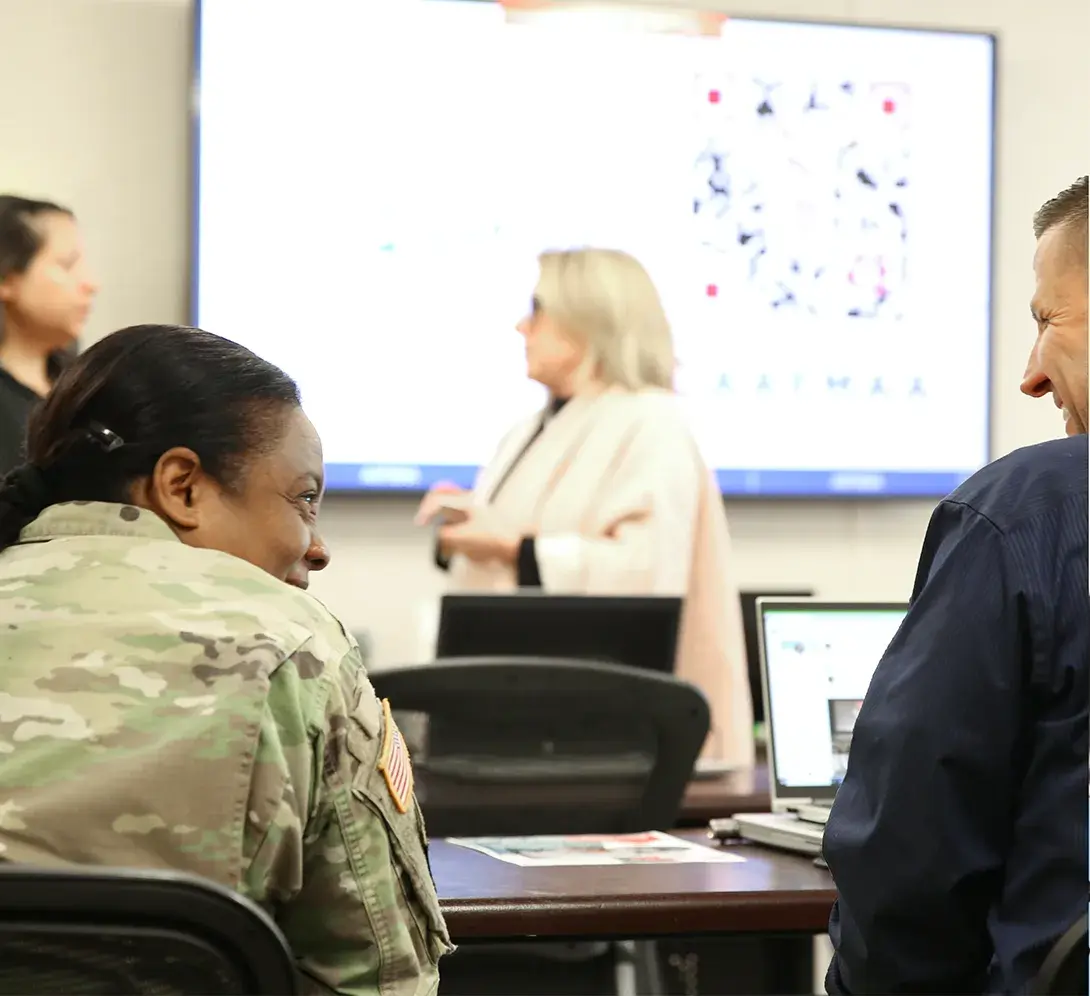 A military woman and a man laughing in a classroom