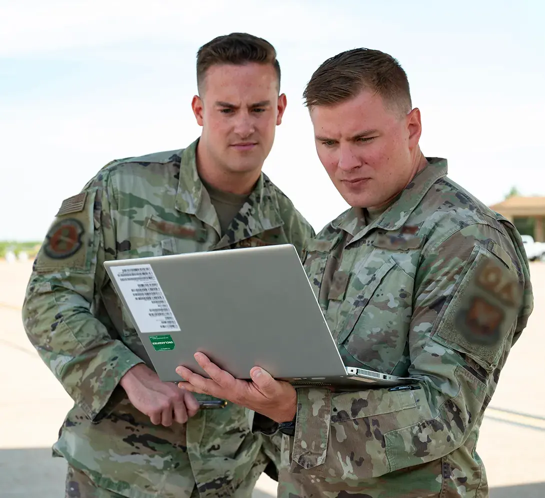 Two people in military uniform using a laptop.
