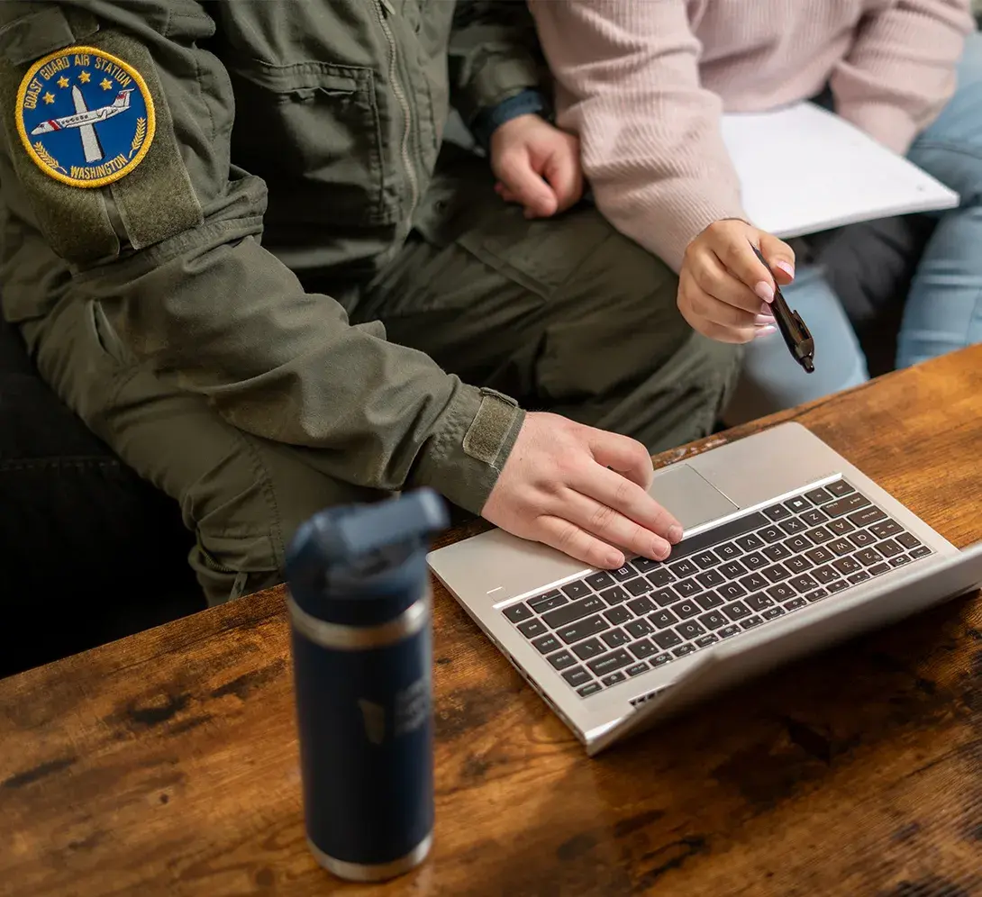 A person in military uniform using a laptop.