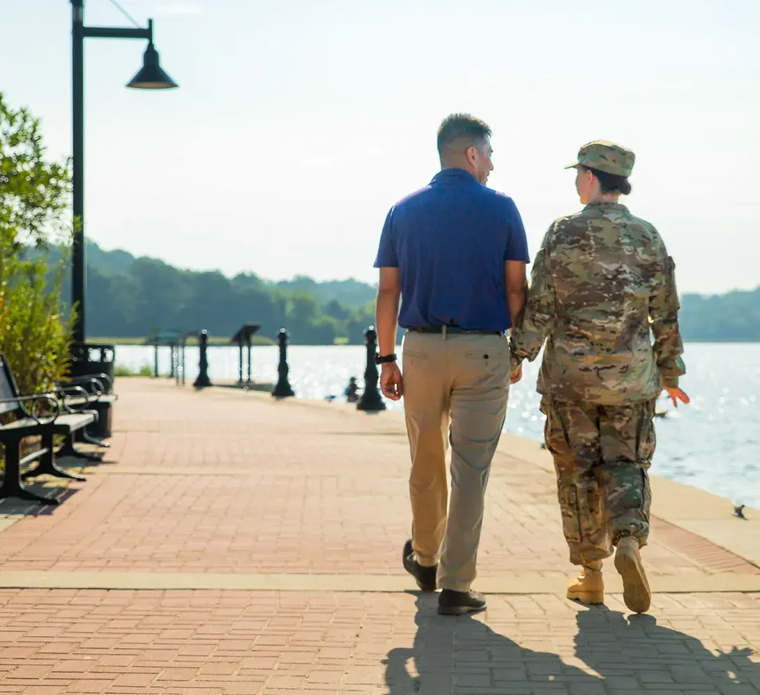 Two people walking down a boardwalk.