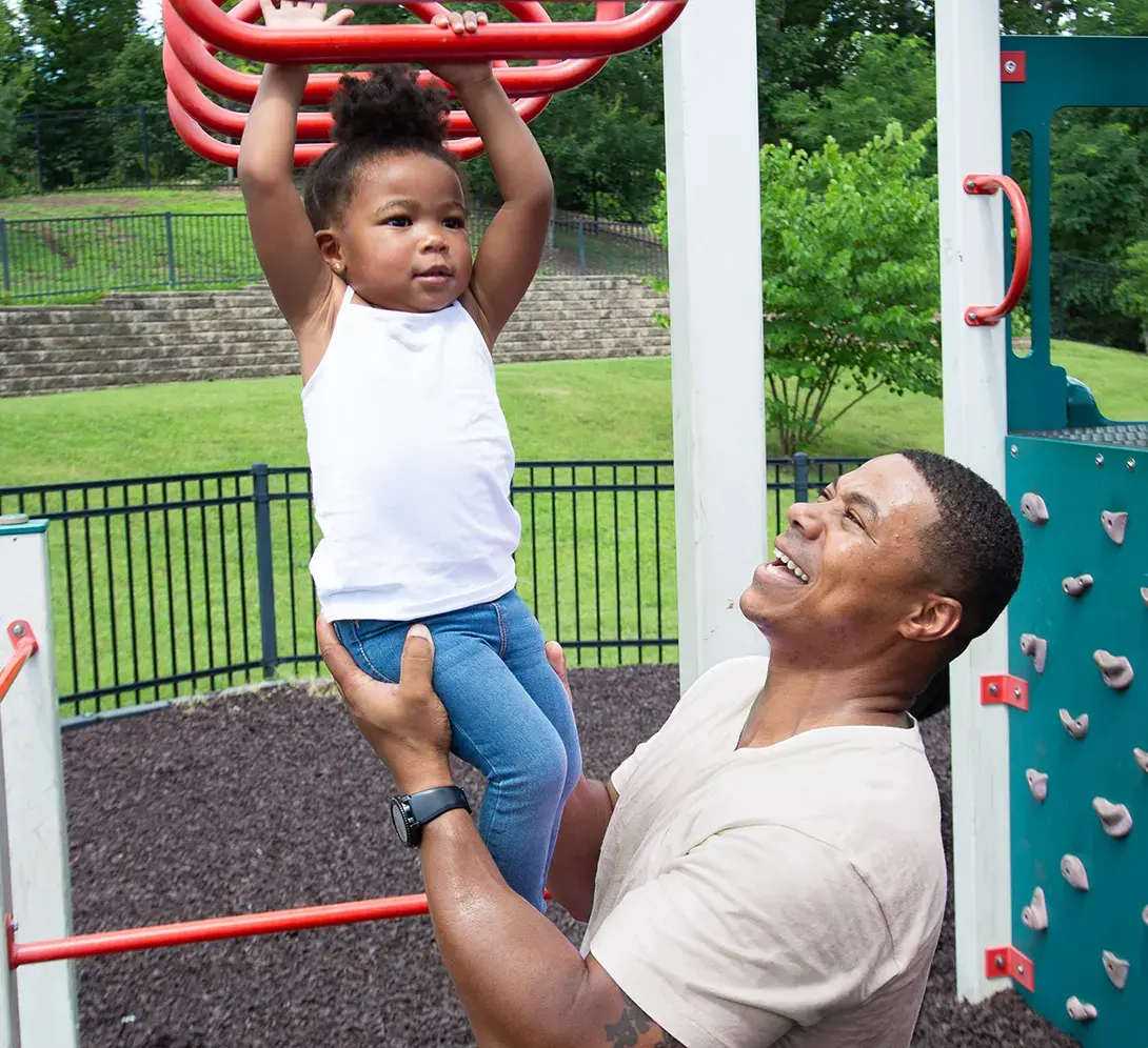 A father helping a small child at the playground.