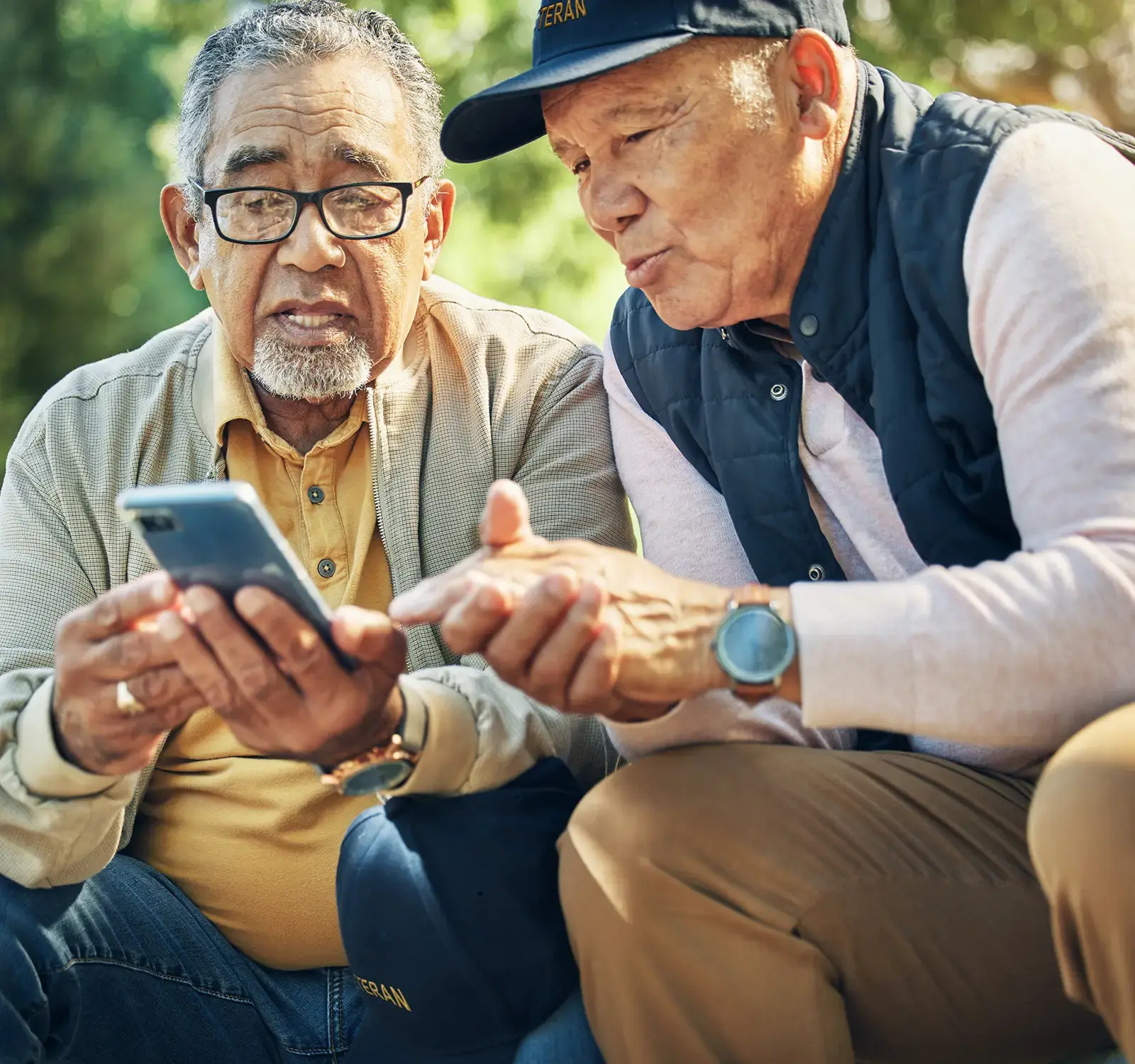 Image of two people sitting in a park using a phone.