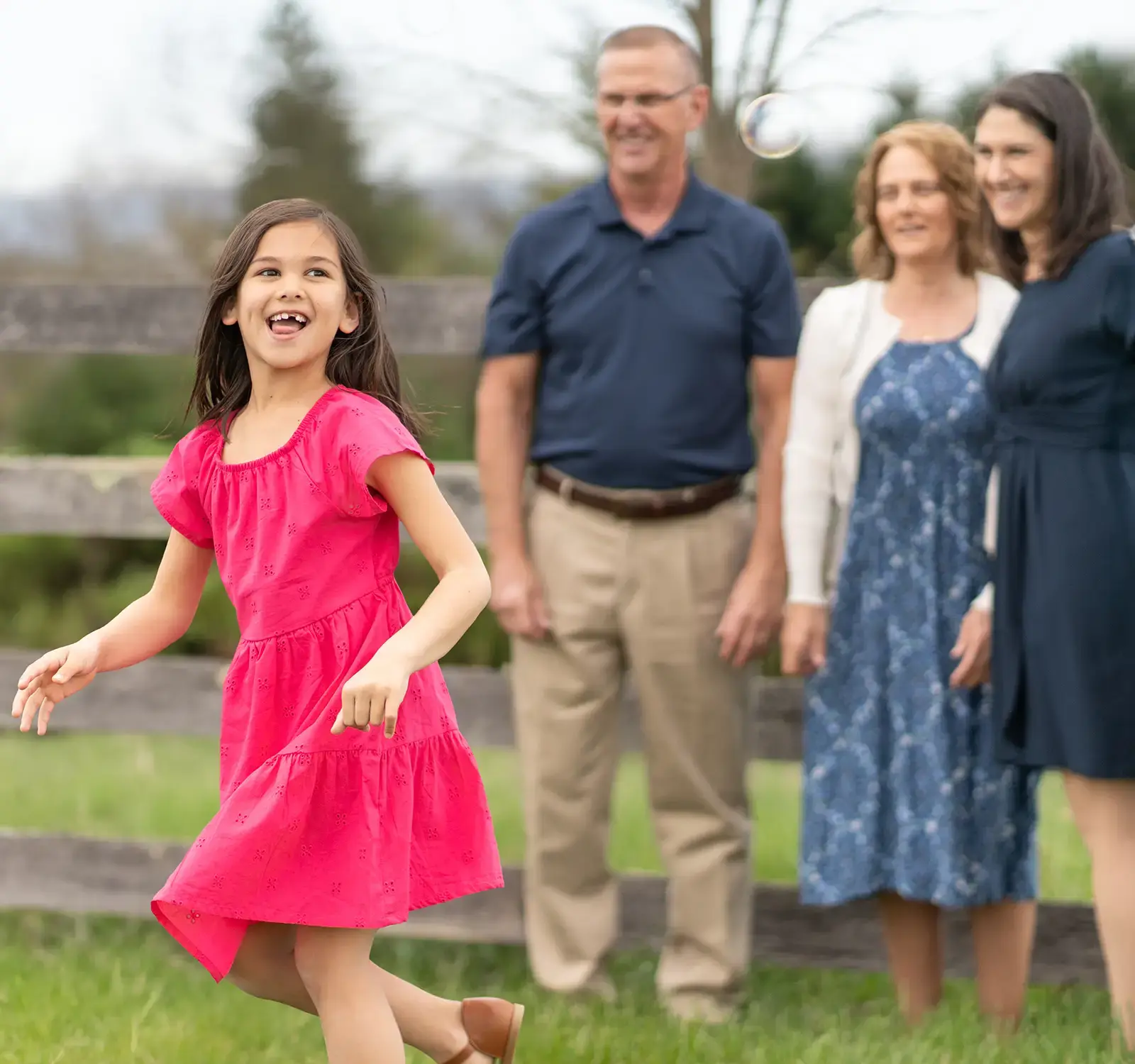 Image of three adults watching a child play.