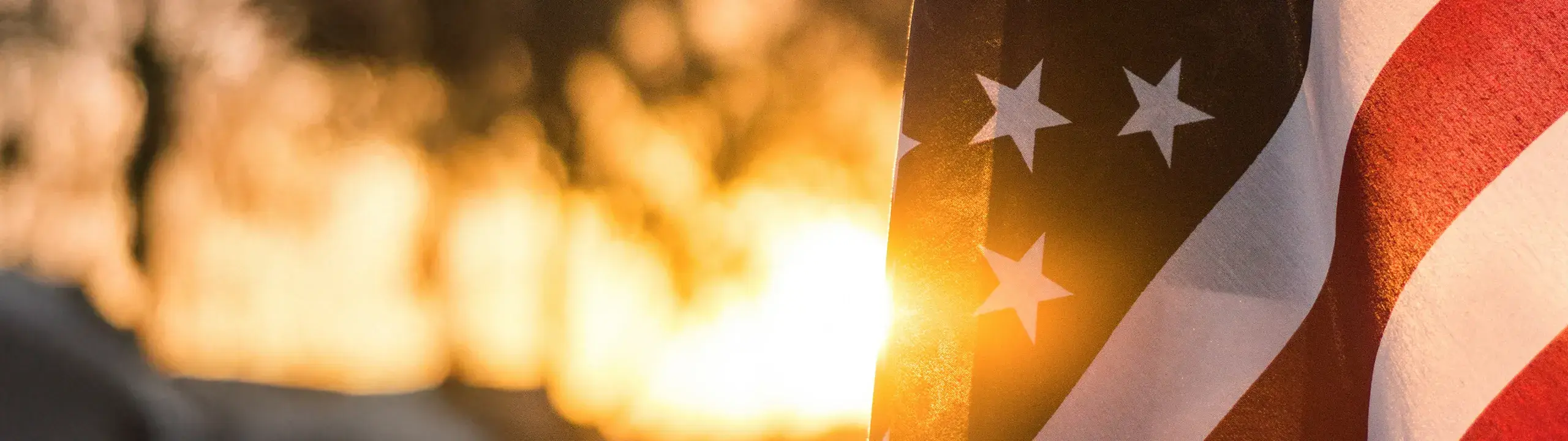 Flag of the United States of America partially appearing on the screen, with a sunset in the background