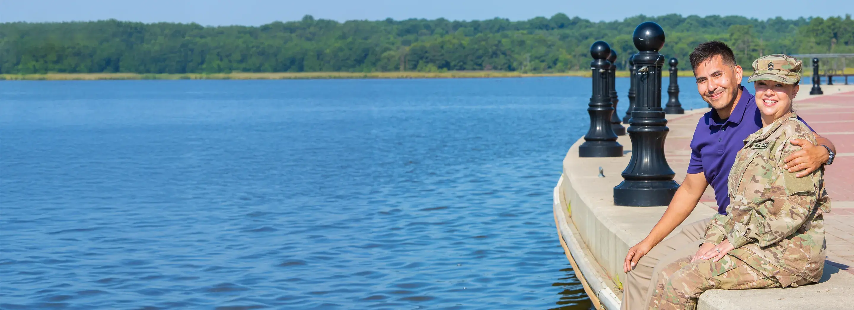 Two people sitting on the side of a lake.