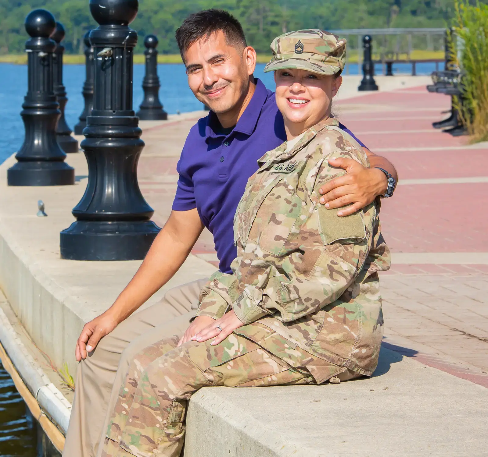 Two people sitting on the side of a lake.