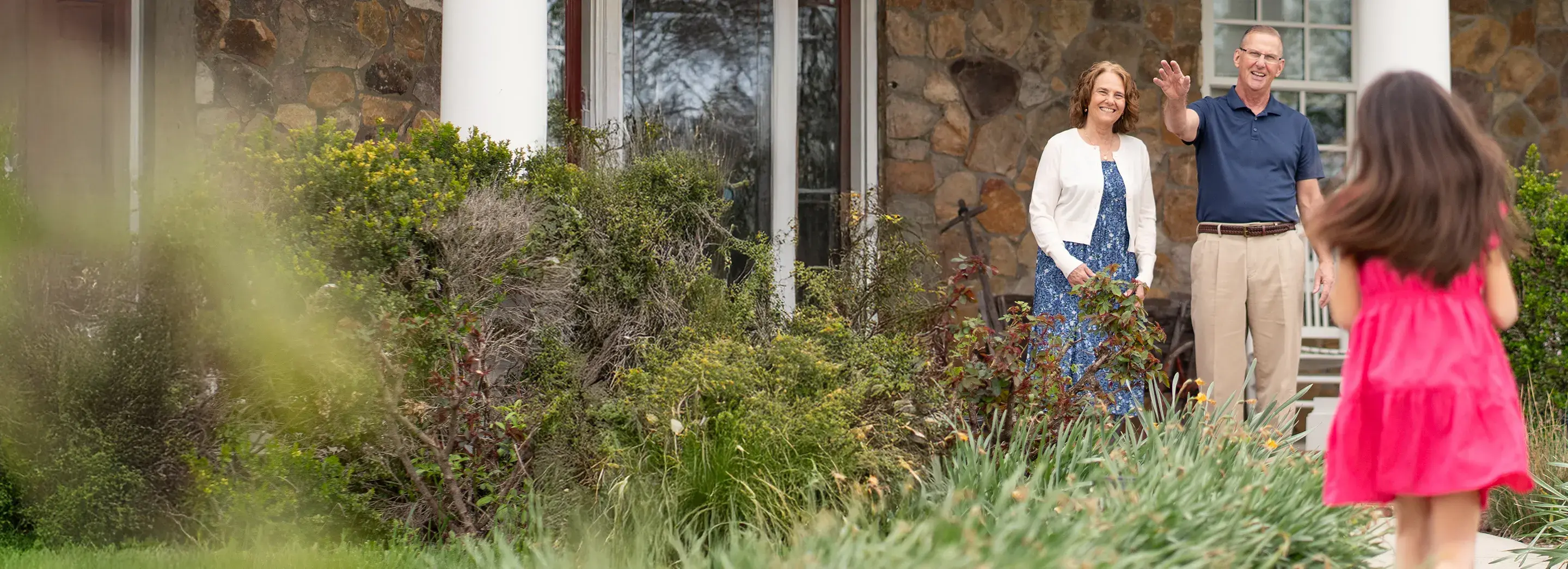A child running towards adults standing on the porch.