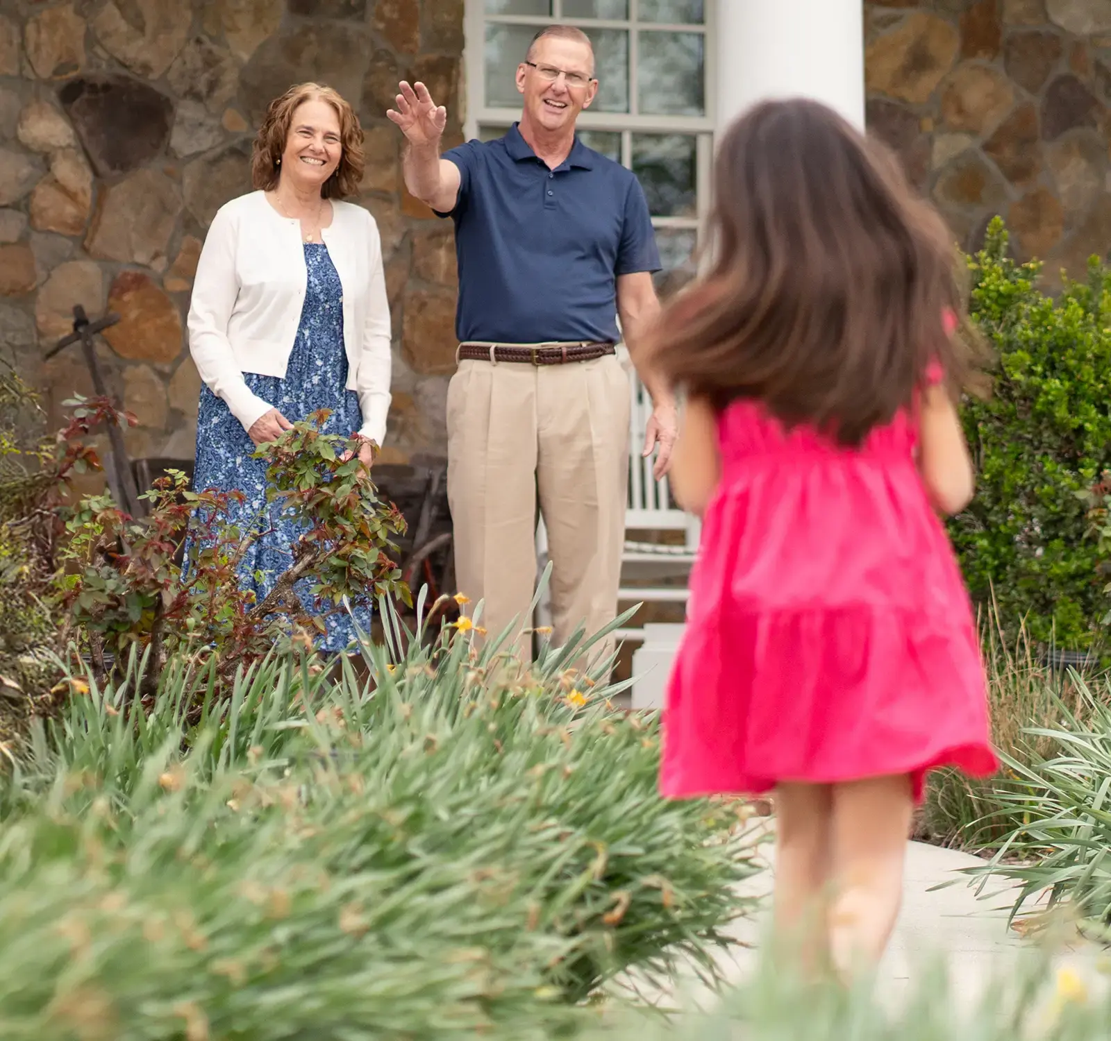 A child running towards adults standing on the porch.