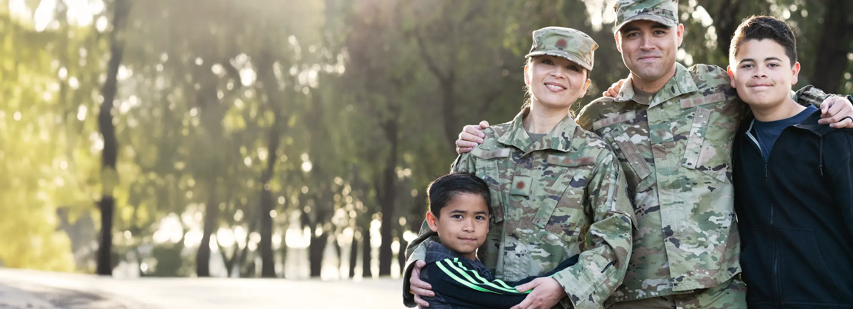 Two adults in military uniform and two children embracing in a posed picture.