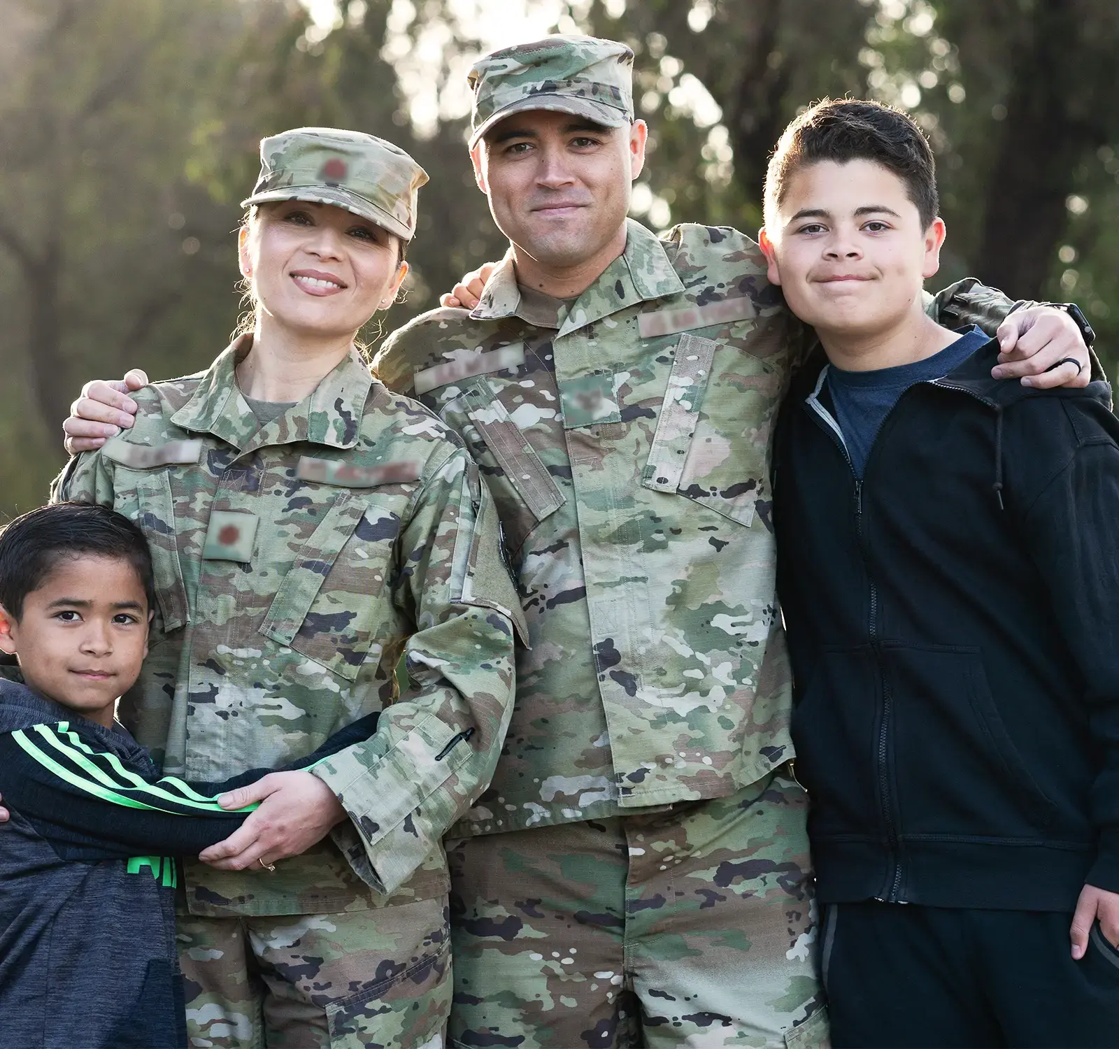 Two adults in military uniform and two children embracing in a posed picture.