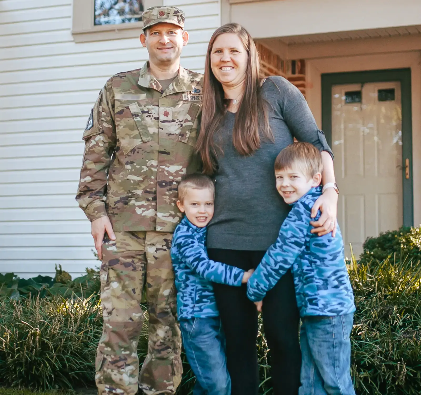 A family posing outside a house.