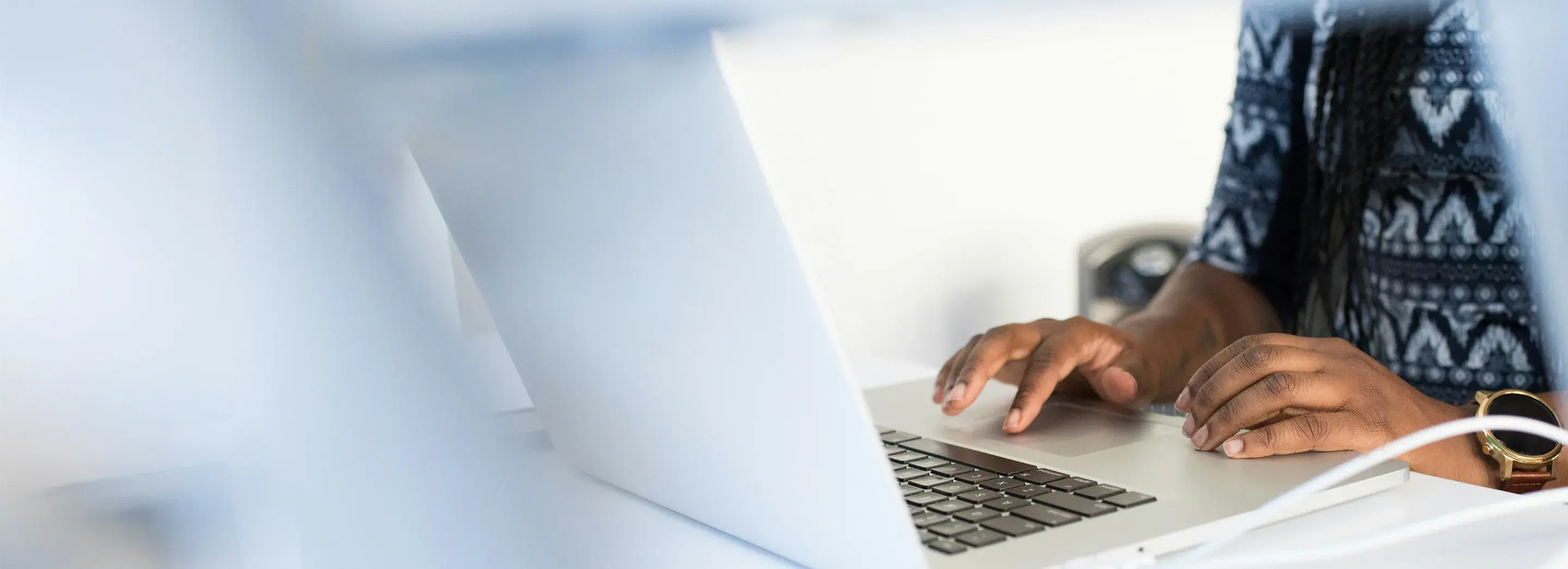 Someone sitting at a desk using a laptop.