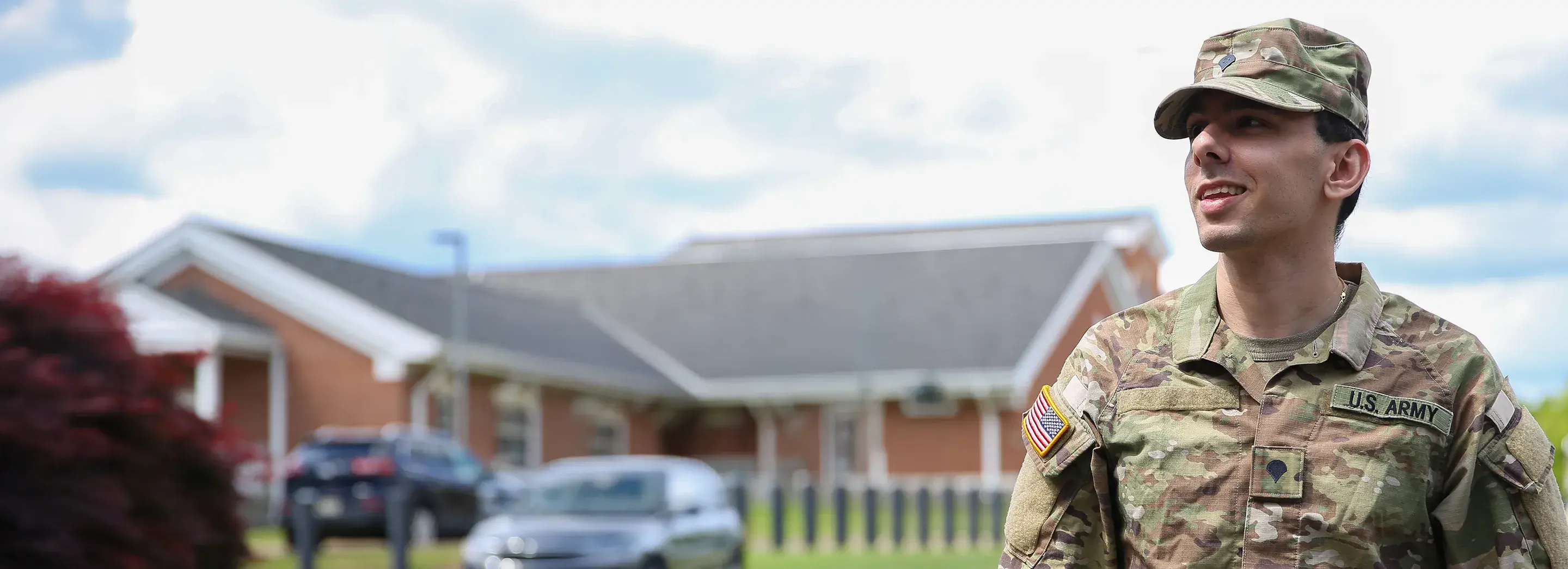 Image of a person in military uniform standing in front of a house.