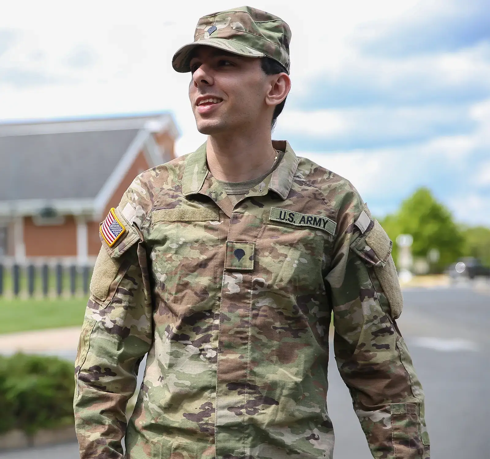 Image of a person in military uniform standing in front of a house.