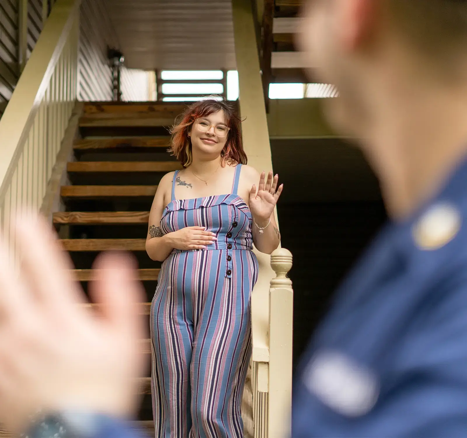 Image of a person standing at the bottom of a staircase waving to someone in the distance.