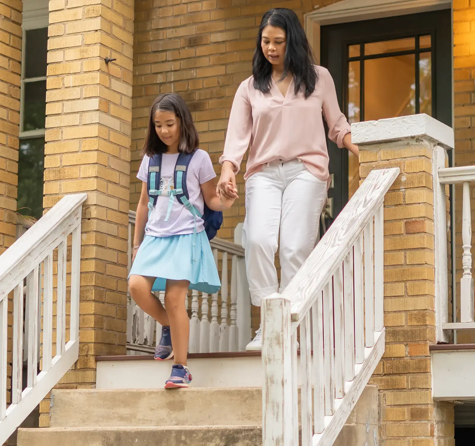 A mother and a child walking down the steps of a house.