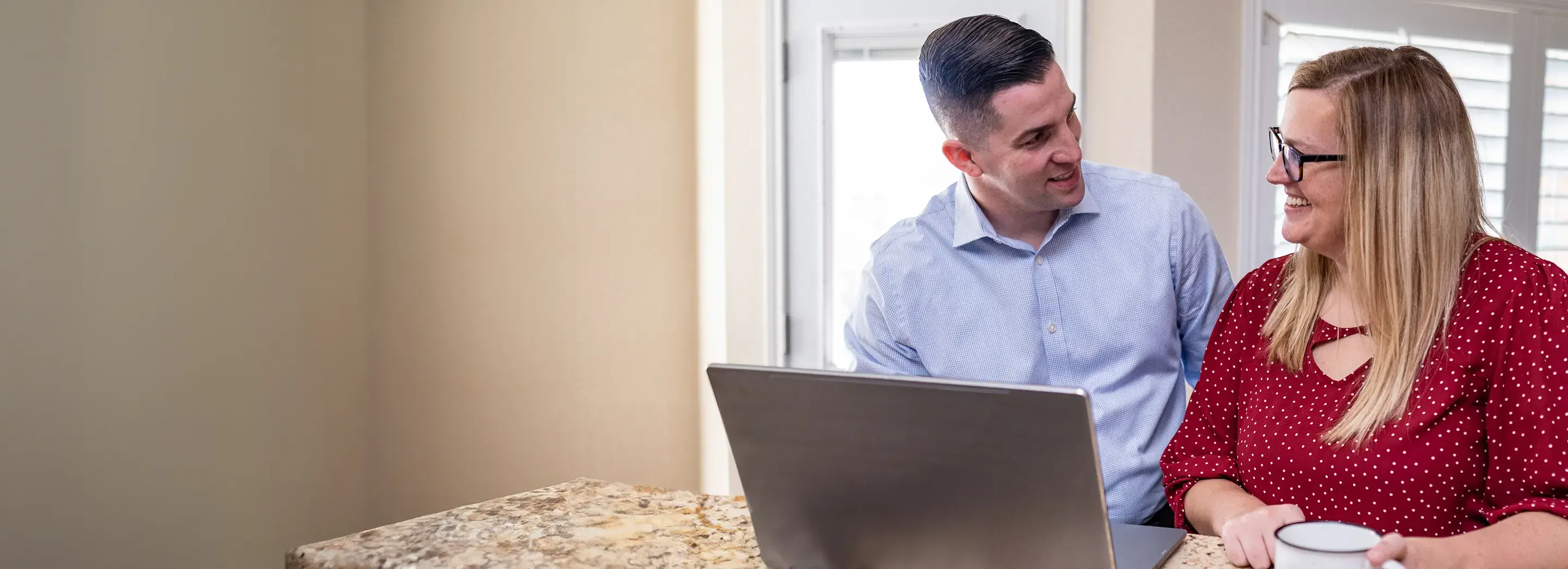 Two adults sitting at a table using a computer.