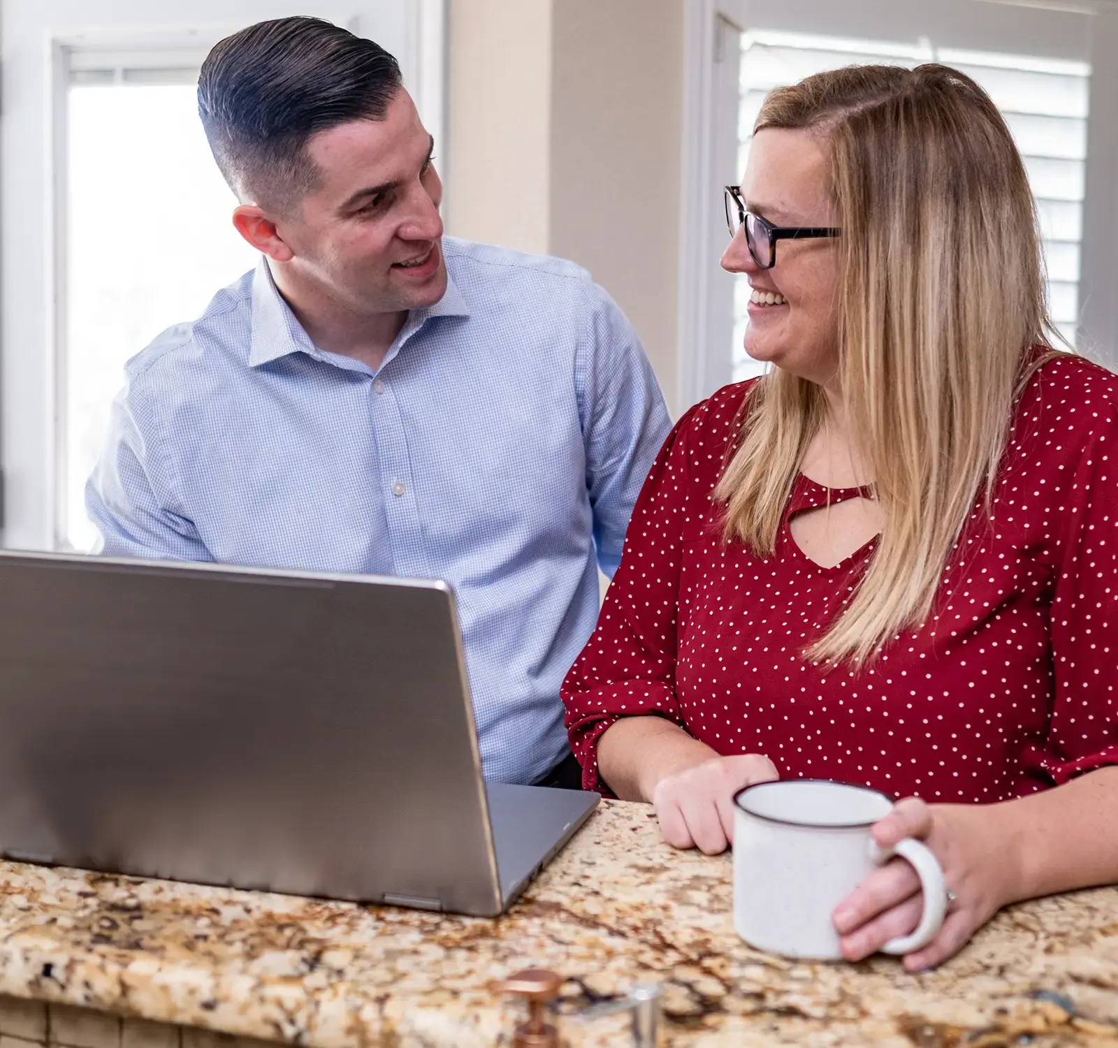 Two adults sitting at a table using a computer.