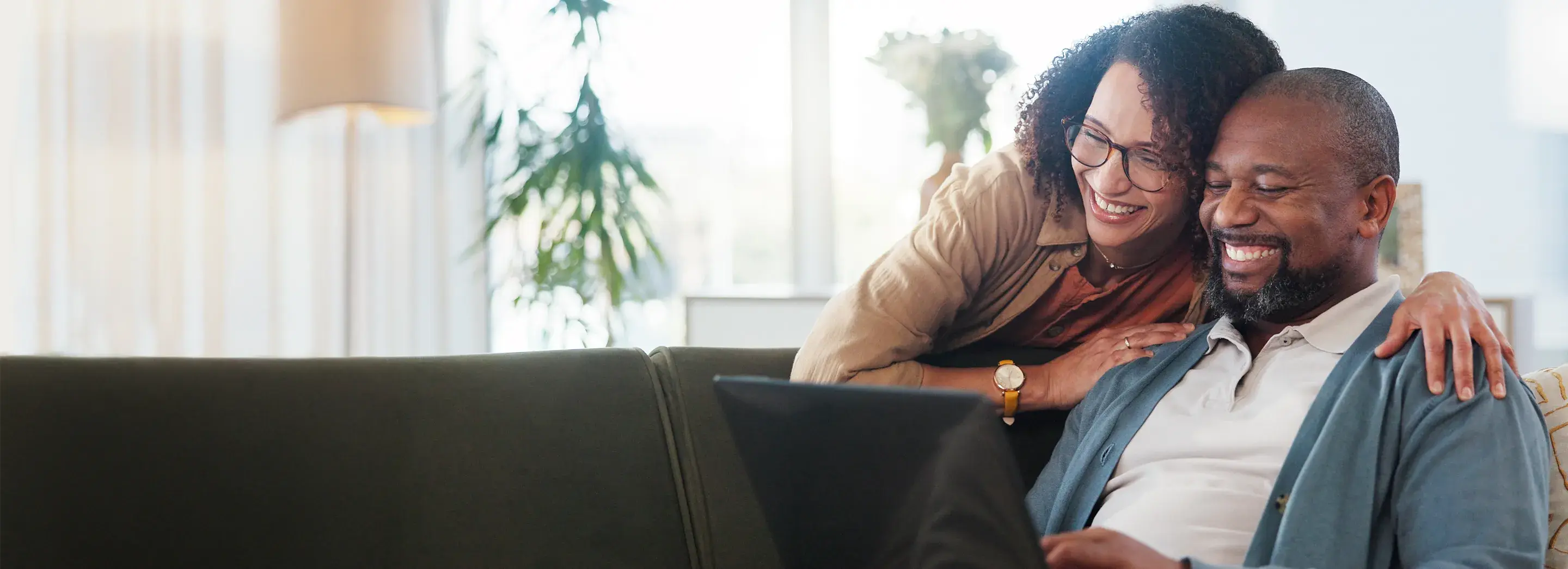 A couple sitting on a couch using a laptop.