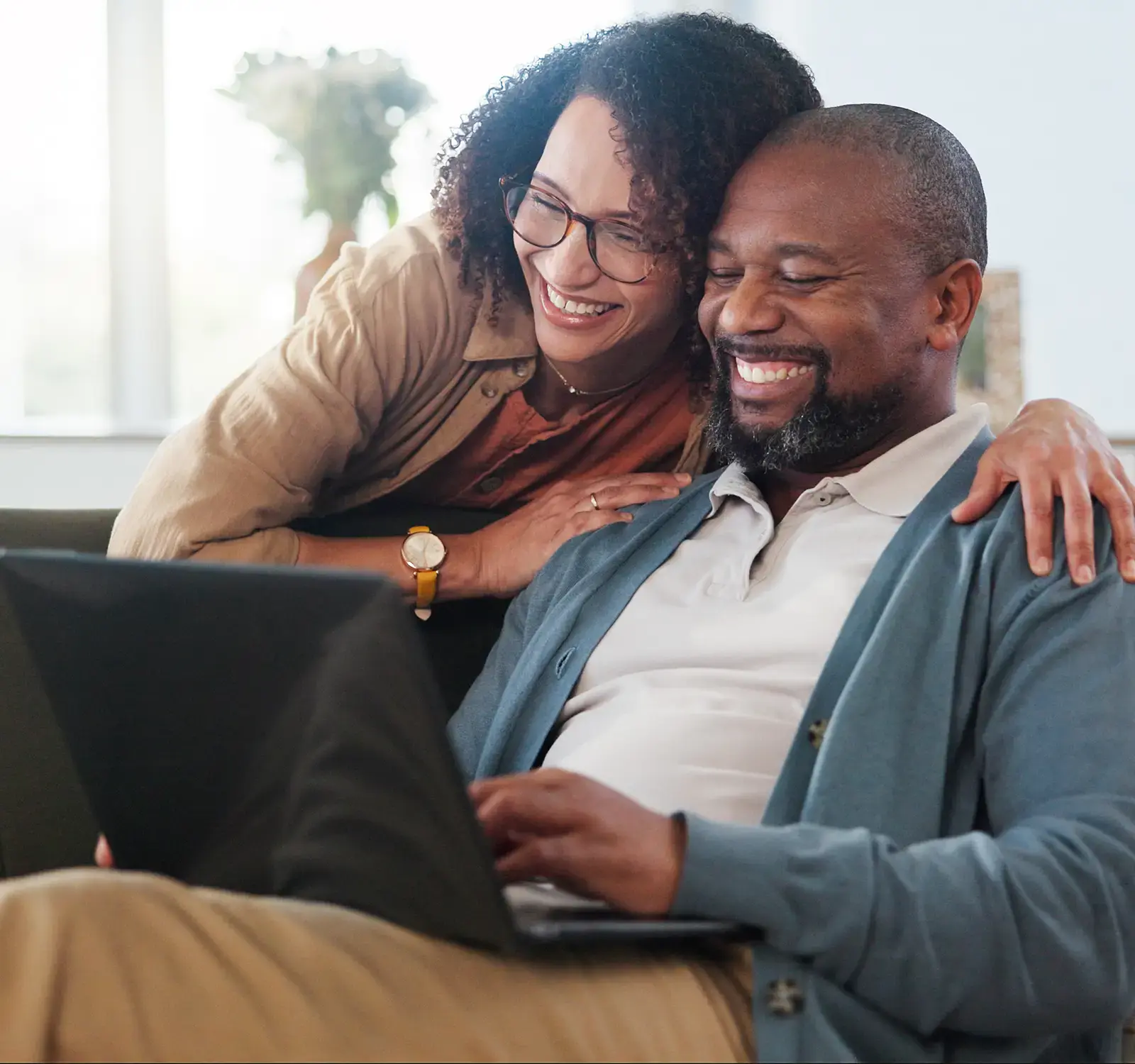 A couple sitting on a couch using a laptop.