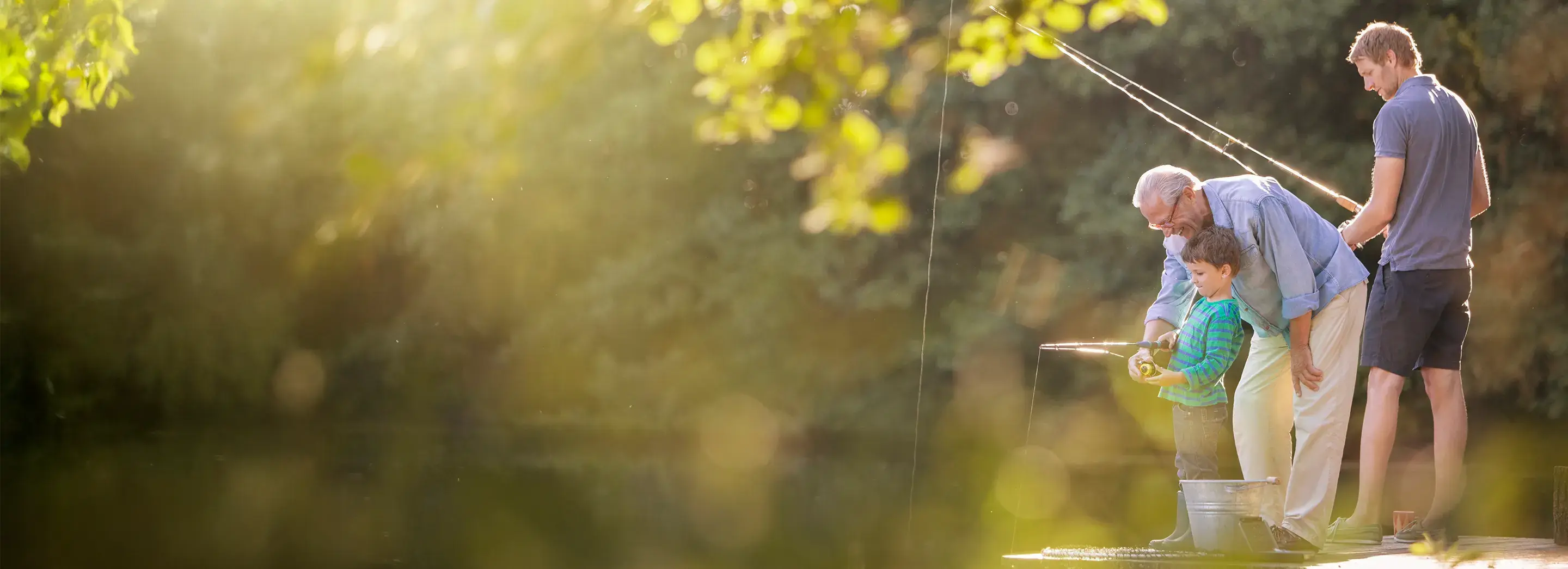 3 generations of men fishing, with a grandfather instructing his grandson.