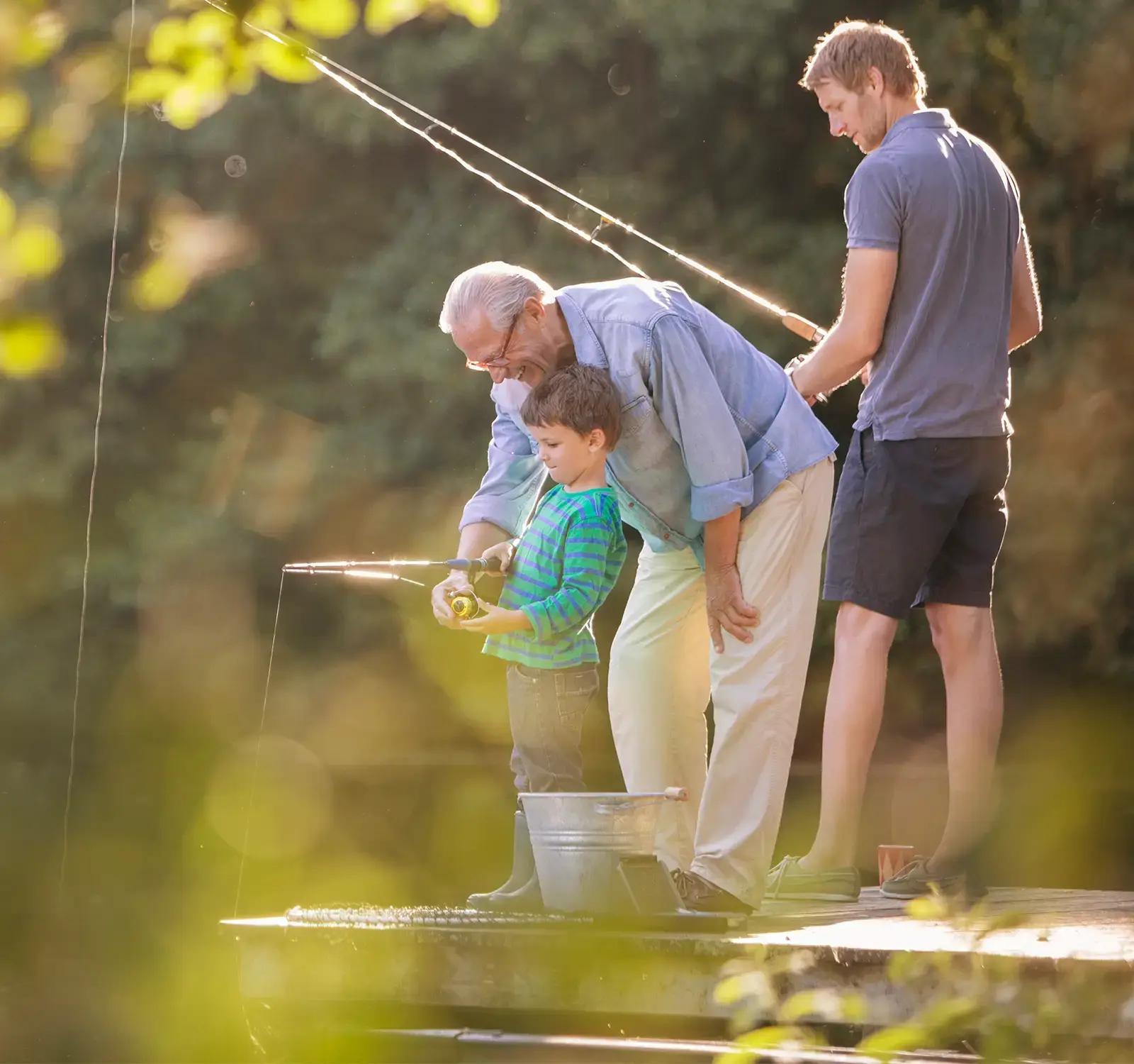 3 generations of men fishing, with a grandfather instructing his grandson.