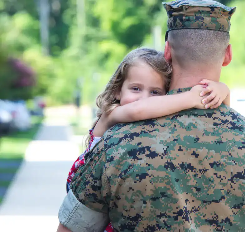 Image of a military personnel hugging a young child